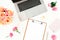 Silver laptop, roses flowers and clipboard on white background. Flat lay. Top view. Women`s blog concept
