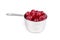 Silver measuring cup containing maraschino cherries side view
