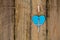 Silver metal crucifix hanging with a blue heart on string against rustic wooden background