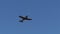 Silver metal fuselage vintage propeller airplane in flight in bright blue sky