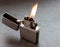 Silver metal lighter with flame.