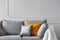 Silver, orange and grey pillows on comfortable sofa