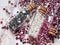 Silver and pink rhinestones and white pearls in glass jars with wooden lids on a marble background