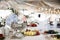 A silver pot with a flower bouquet in it is standing on the table alongside with some plates with food