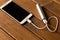 Silver power bank charging smartphone on wooden table