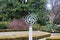 A silver and purple spherical sculpture surrounded by lush green trees and plants with blue sky and clouds