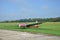Silver and red glider stands on grass landing strip in small country airport while the weather is nice