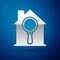 Silver Search house icon isolated on blue background. Real estate symbol of a house under magnifying glass. Vector