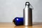 Silver and shiay blue thermo bottle on wooden table.