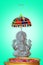 Silver statue of hindu god vinayagar and front of water bowl with flowers. blue background