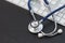 Silver stethoscope lying down on white keyboard, on black background. stock image photo. remote diagnostics