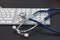 Silver stethoscope lying down on white keyboard, on black background. stock image photo. remote diagnostics