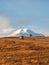 A silver SUV is driving along the highway route to the dawn snow-covered Elbrus. Autumn beautiful road through the mountain desert