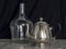 Silver Teapot and Demijohn Black Background Marble Table