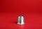 Silver thimble on red background. Sewing accessory