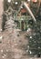 Silver toy Christmas tree with a star in front and blurred Christmas house away. Drawn snow. Background for a