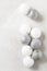 Silver and white Christmas Tree Balls on a light mottled gray surface. Vertical with copy space