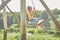 Similing little girl swinging on a large rustic wooden swing in the park, sunlight