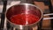 Simmering raspberry sauce in saucepan.