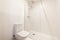 A simple bathroom with a porcelain toilet and a glass-enclosed shower stall with chrome faucets and shower head