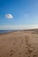 Simple beach background. Single fluffy white cloud in blue sky.