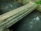 A simple bridge made of bamboo over a water channel.