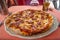 Simple and cheap pizza with cheese and sausages served at table outdoor in Venice, Italy, summer, details