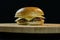 Simple cheeseburger on a wooden board black background