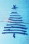 Simple Christmas tree arranged from wooden sticks, driftwood an wooden winter blue background.