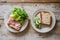 Simple and clean, the photo displays two white plates of appetizers on a light wooden table. One plate contains bread