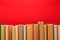 Simple composition of hardback books, raw of books on wooden deck table and red background - Image.