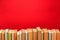 Simple composition of hardback books, raw of books on wooden deck table and red background - Image.
