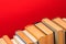Simple composition of hardback books, raw of books on wooden deck table and red background - Image.