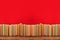 Simple composition of hardback books, raw of books on wooden deck table and red background - Image.