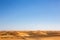 Simple desert landscape with golden sand dunes, low horizon, crystal blue sky, copy space, background
