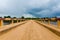 Simple dirt road bridge over tropical river with dramatic clouds in Republic of Congo, Africa