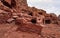 Simple dwelling ruins - cave like holes in stone wall, cloudy sky above mountains - as seen in Petra, Jordan