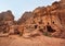 Simple dwelling ruins - cave like holes in stone wall, moon above mountains - as seen in Petra, Jordan