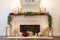 a simple yet elegant fireplace with a gold and red ornaments, candles, and greenery