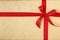 Simple, festive Christmas gift present background with sustainable recycled kraft wrapping paper and bright red ribbon bow