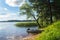 Simple fishers` motorboat, moored to the riparian forest of the lake Seliger under the blinding sunlight, Russia.