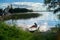 Simple fishers` motorboat, moored to the shore and view of the spaces of the lake Seliger under the blinding sunlight, Russia.