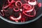 Simple food ingredients, red onion rings and slices of beetroot on pot on kitchen stovetop