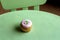 Simple green table and chair with one strawberry cupcake with thick, creamy frosting