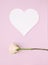 Simple heart shape card on muted pastel pink color background with white rose