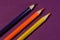 A simple image. yellow, Orange and blue pencils on a purple background