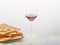 On a simple laconic white background on a glass dish lies matzah, the Hebrew Passover bread. There is a glass of red wine nearby.