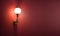 Simple lamp hangs on red wall and illuminates it, space for text