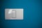 Simple light switch, white on a blue wall with