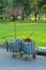 A simple metal gardening trolly, with rubbish bins, broom and dustpan of natural fibers,